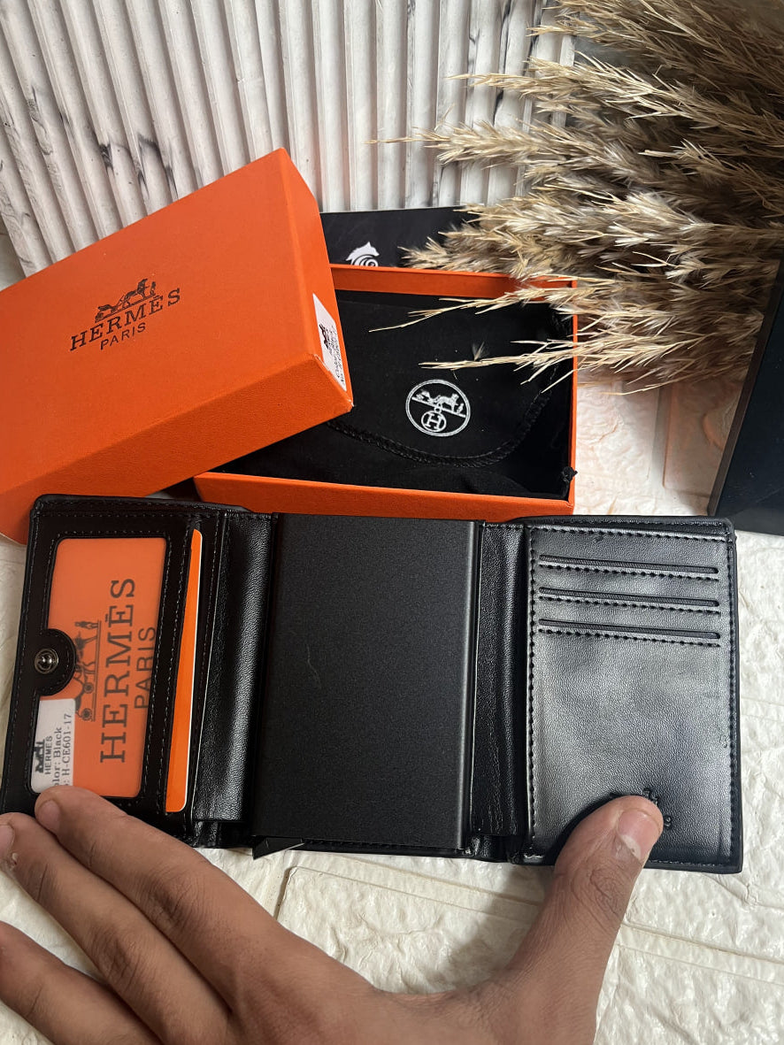 Black Hermes wallet with orange box on a textured surface